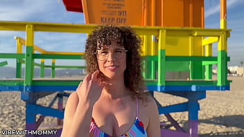 A mature Jewish woman engages in sexual activity with a random man at the beach, both wearing bikinis